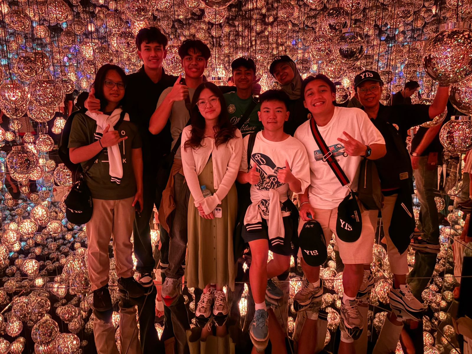 YIS students standing among glowing light installations at teamLab Borderless